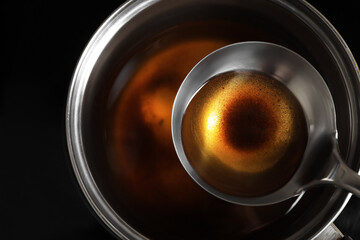 Saucepan and ladle with used cooking oil on stove, closeup