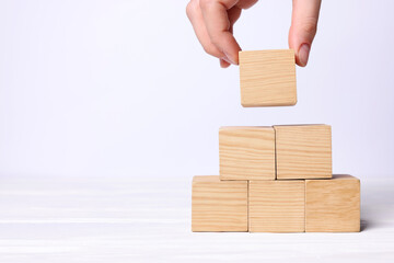 Woman building pyramid of cubes on white background, closeup with space for text. Idea concept