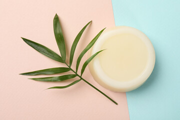 Solid shampoo bar and green leaf on color background, top view. Hair care