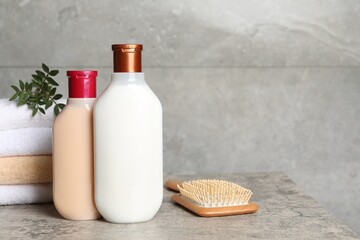 Bottles of shampoo, hairbrush and stacked towels on grey table, space for text