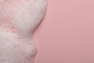 Fluffy soap foam on pink background, top view. Space for text