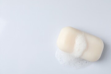 Soap with fluffy foam on white background, top view. Space for text