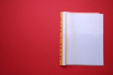 File folder with punched pockets and paper sheets on red background, top view. Space for text