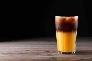 Tasty refreshing drink with coffee and orange juice on wooden table, space for text