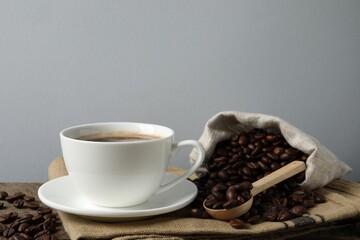 Cup of aromatic coffee and beans on wooden table