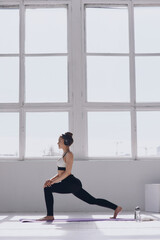 Fototapeta premium Confident young woman doing stretching exercises while practicing in front of the window