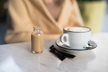 a fragrant and warm mug of cappuccino with a drawing heart,  girl  hold in hands.
