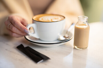 a fragrant and warm mug of cappuccino with a drawing heart,  girl  hold in hands.