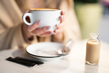 a fragrant and warm mug of cappuccino with a drawing heart,  girl  hold in hands.