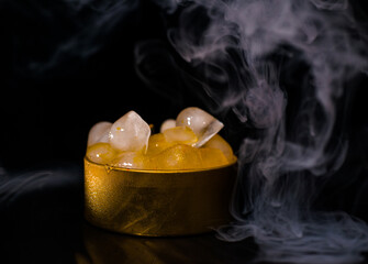 Ice in a golden box with smoke, colorful smoke, blue smoke, gray smoke, ice in syrup, delicious ice. space picture on dark background