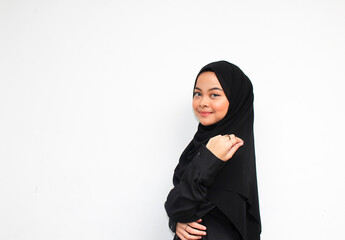 Attractive beautiful Asian woman in hijab and black dress smiling happy and looking confident isolated over white background