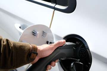 close up and selective focus hand, pushing car charger into a car hub for electric vehicle or electric car our EV car energy.