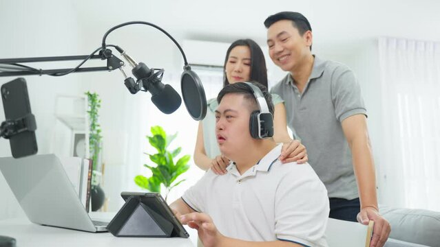 Asian young DJ man speaking on microphone at studio with loving parent