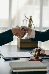 Close-up view of lawyer and client holding hands with scales and hammer next to law adviser concept