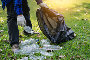 A young man collects plastic bottles and black bags and piles them together to sell to shoppers who collect them for recycling. The concept of waste separation and environmental protection