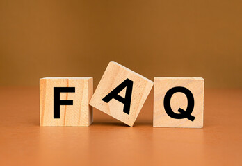 FAQ - frequently asked questions concept. Wooden cubes with words F, A, and Q on a brown background
