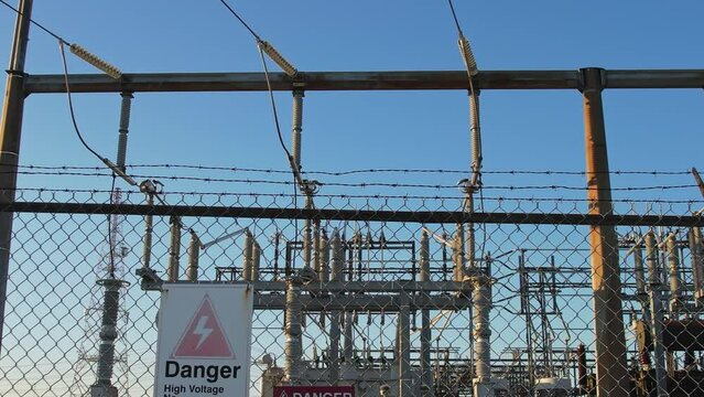 Electrical grid substation and high voltage electric switchyard converter transformer in America. Power station with pylons and distribution cables for city households and EV charging stations.