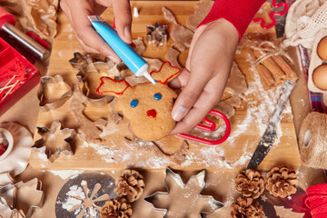 Overhead shot of unrecognizable person decorates reindeer ginger cookie prepares delicious...