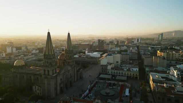 Jaw-dropping, aerial view of majestic and bright sun rolling beyond the horizon in Guadalajara downtown. Picturesque urban landscape with mighty spires of Cathedral. High quality 4k footage
