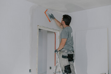 A young builder is plastering a doorway.