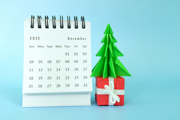 Selective focus of December 2022 desk calendar on blue background with christmas tree, gift and...