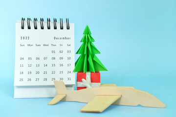 Selective focus of December 2022 desk calendar with airplane model and christmas tree on blue...