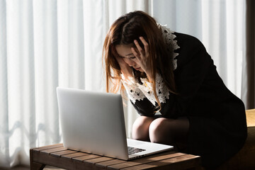 女性はノートパソコンを見て頭を抱えている。