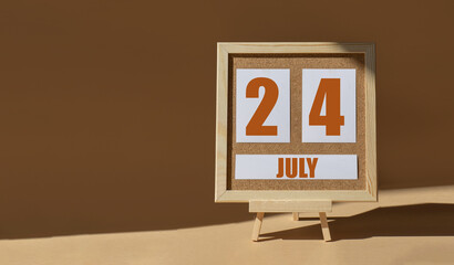 July 24th. Day 24 of month, Calendar date. Cork board, easel in sunlight on desktop. Close-up, brown background.  Summer month, day of year concept
