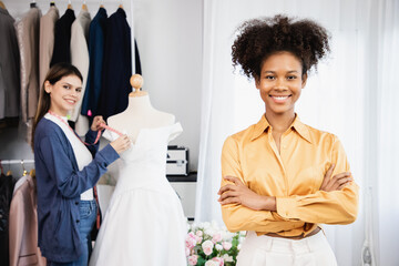 Diversity of cheerful woman owner shop assistant standing in wedding store and with arms cross and...
