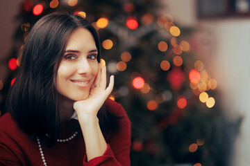 Happy Beautiful Woman Smiling in Front of her Christmas Tree. Portrait of a festive lady celebrating winter holidays at home
