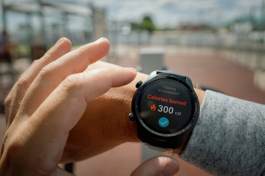 man at the stadium checks the number of calories burned in his smartwatch. Daily exercise in the fresh air for weight loss. all the graphics on the screen are made up.