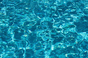 Blue pool water background. Blurred transparent clear calm water surface texture. Water waves in sunlight with copy space.