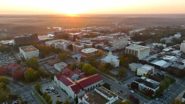 Cinematic aerial establishing shot of Athens Georgia, home of University of Georgia Bulldogs. College town at sunrise magic hour with warm light on horizon.