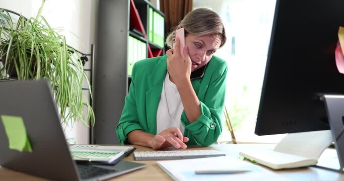 Busy manager consults client on phone, manages statistical data on laptop