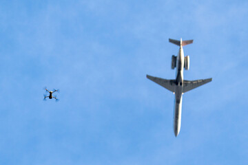 The drone is flying on low height under airplane with flying above the drone. Concept pictures attention drones. 