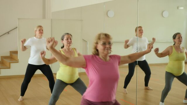 Mature women dancing aerobics at lesson in the dance class 