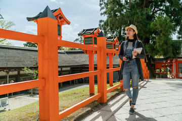 full length of cheerful Asian Japanese girl tourist carrying travel book enjoying landscape around...
