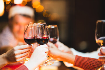 Glasses of champagne and wine in hands of people at party. happy friends or family having christmas dinner at home.
