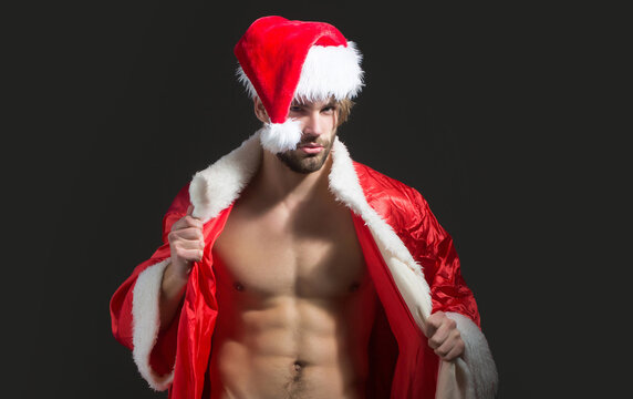 Christmas sexy man. Muscle man with bare torso at xmas. Santa with muscular body. Christmas party and sex games. Handsome sexy santa claus guy on black background.