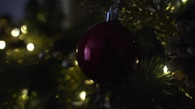 Decorating Christmas tree with balls on the background of bright festive lights 