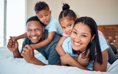 Fototapeta premium Happy, smile and portrait of a family in a bedroom to relax, play and bond together at their home. Happiness, love and parents relaxing with their children while being playful on a bed at their house