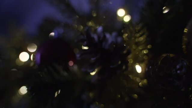 Decorating Christmas tree with balls on the background of bright festive lights 