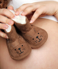 Brown children's shoes on a pregnant tummy. Funny children's shoes on a pregnant tummy.