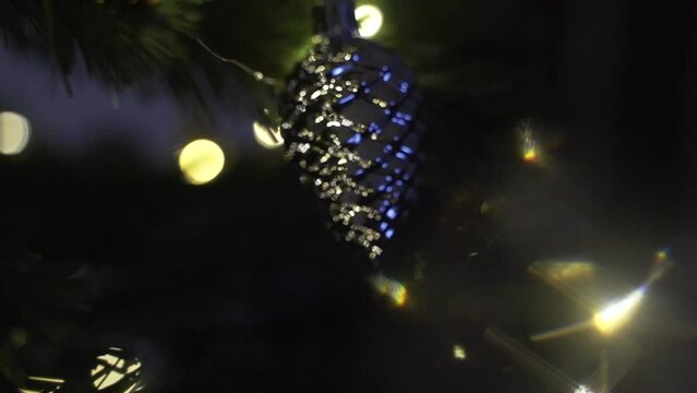 Decorating Christmas tree with silver cone on the background of festive lights 