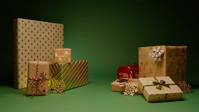 Merry Christmas atmosphere stacks of beautiful gifts in kraft paper with shiny green and silver pattern. Cinematic shot for commercial message background with center space for Sale copy or Promo text