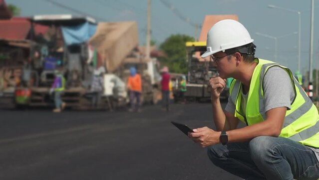 Asian engineers watch road rebuilding and inspect the construction of asphalt the road at the construction site.