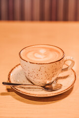 A cup of coffee with milk on a brown background. Hot cappuccino on the table