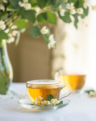 Jasmine flowers in vase and two glass cups of green tea.