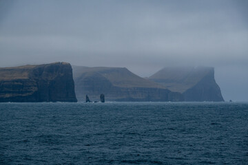 Impressive steep cliffs and rocky coastline silhouette coast of Faroe Islands in Atlantic Ocean on...
