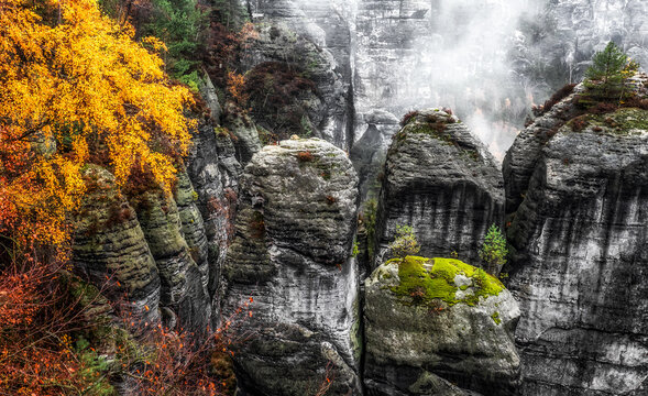 Misty weather in colorful autumn forest and rock formations